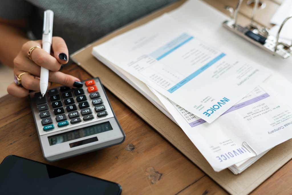 a women holding a pen while using a calculator