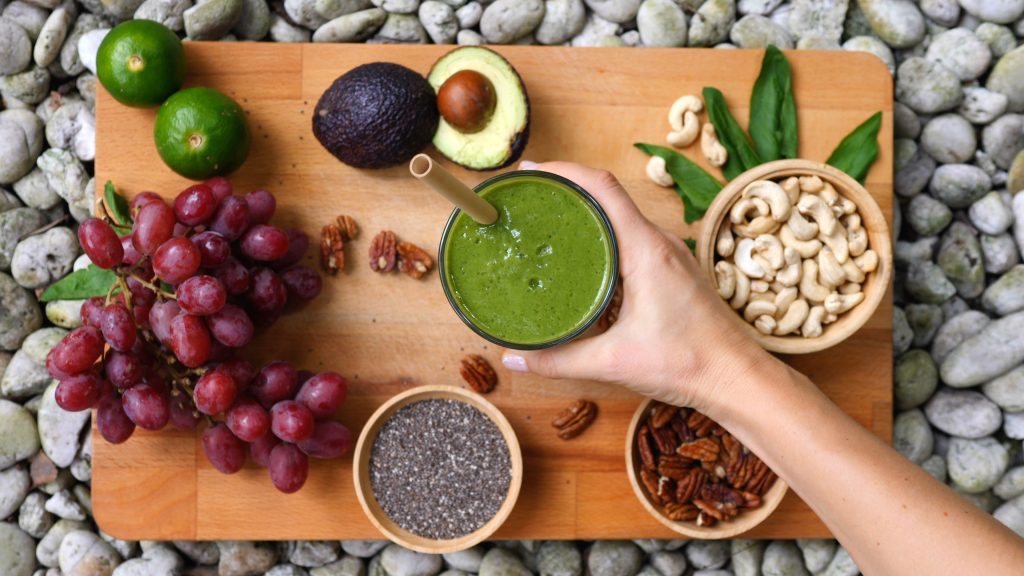 Top View Of Female Hand With Healthy Vegan Green Smoothie.