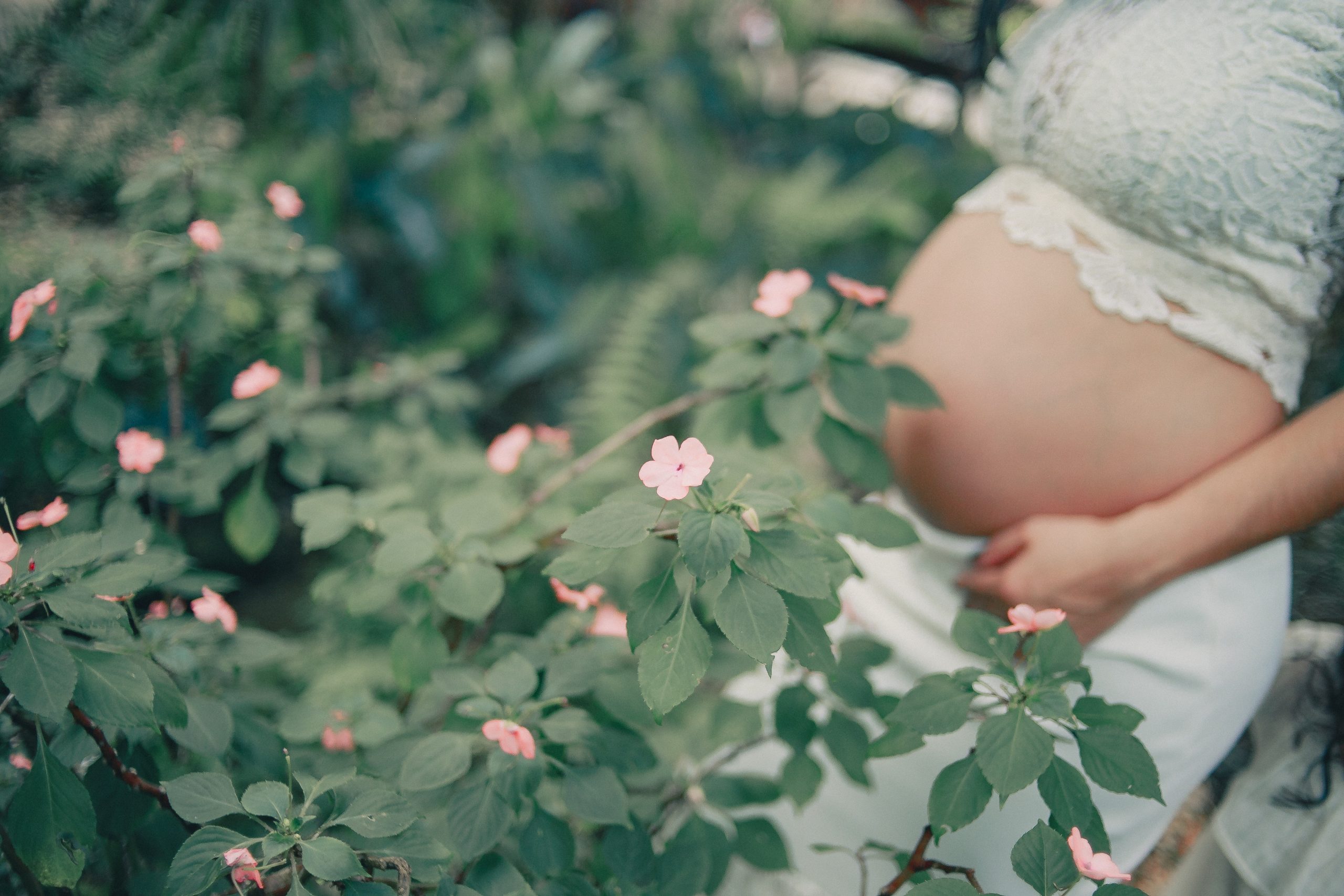 a pregnant women standing near flowers