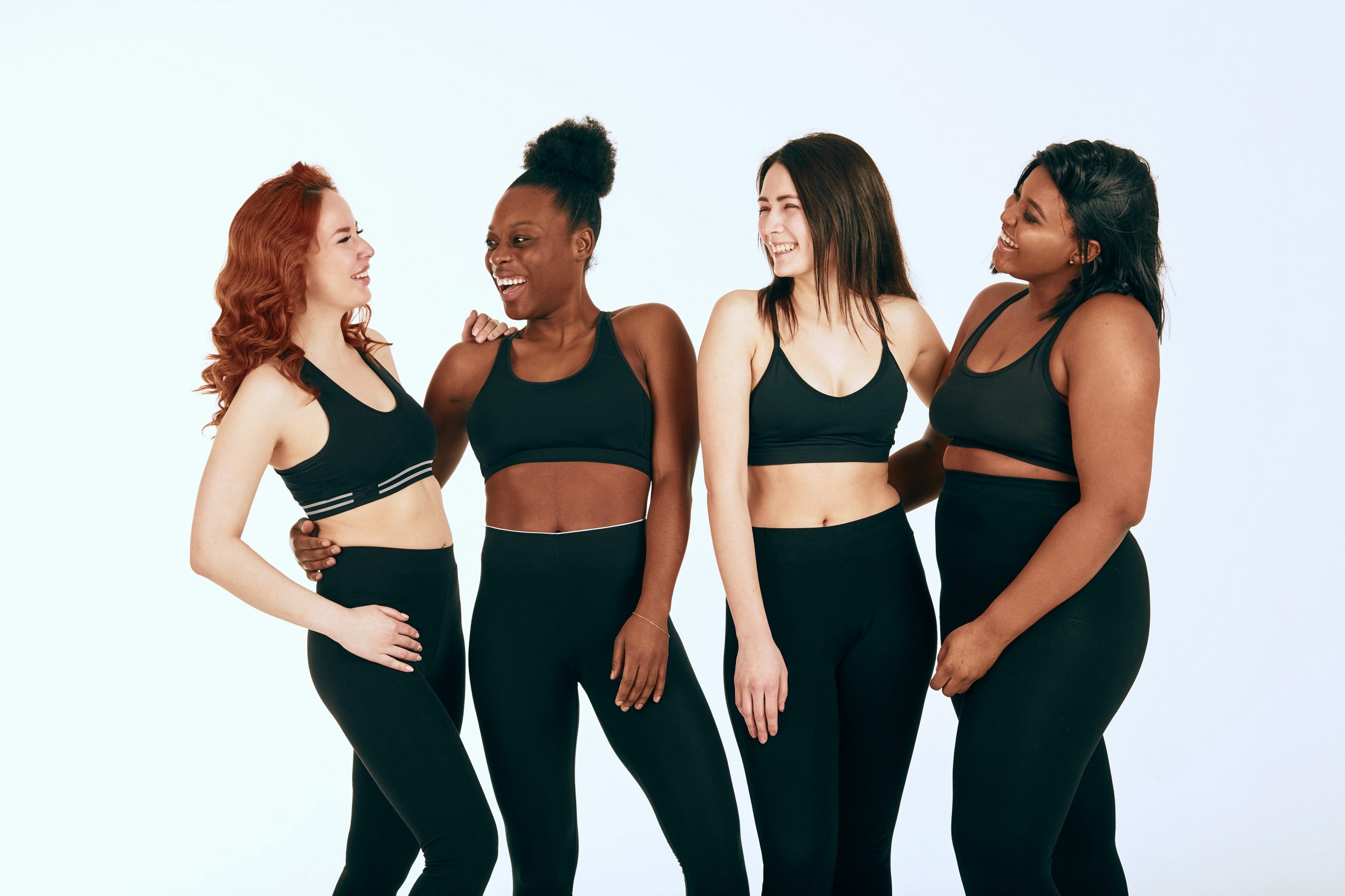 Multiracial females with different size and ethnicity stand together and smile.