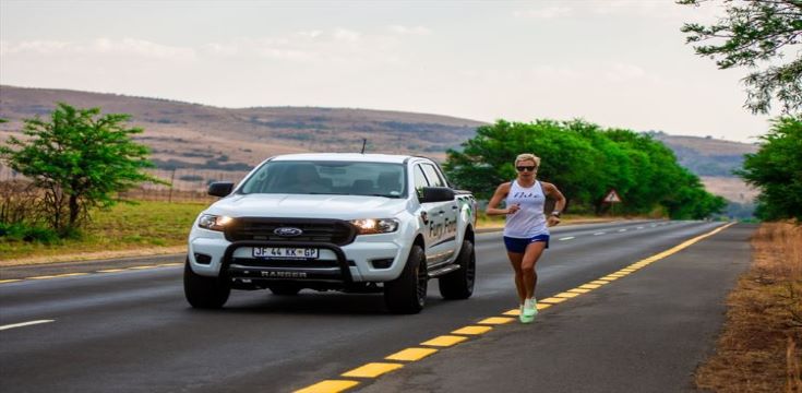 female athlete running besides a motor vehicle