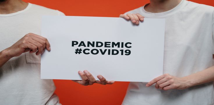 people holding white paper with pandemic covid 19 text