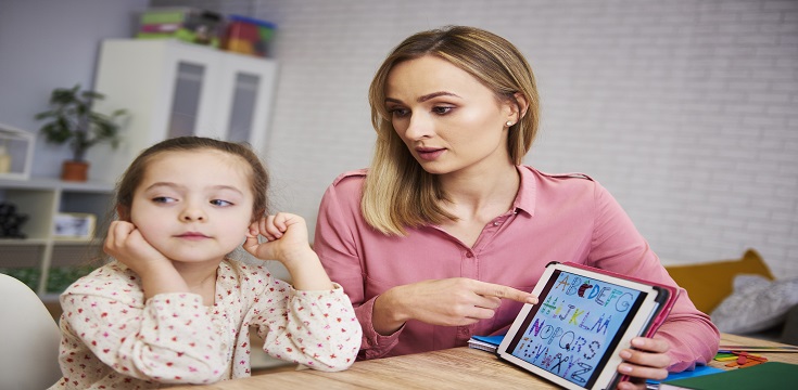 Bored girl and her mother studying with laptop at home