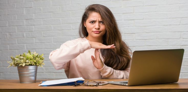 young-woman-at-desk-showing-timeout-or-stop-hand-gesture
