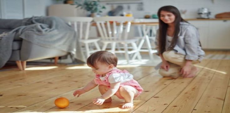 mother-watching-baby-daughter-playing-orange