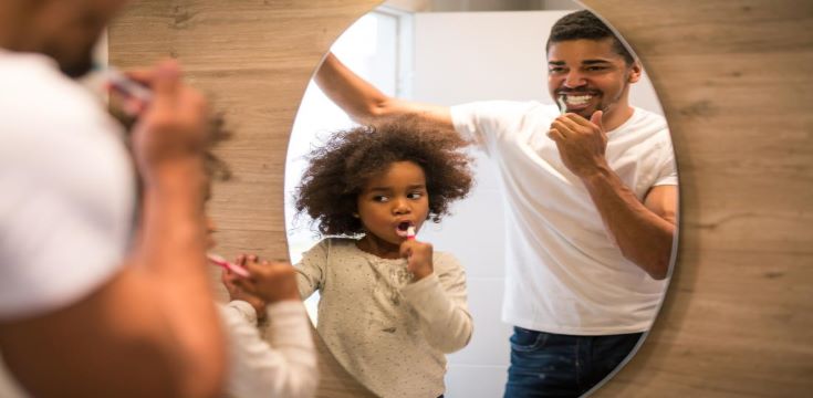 father-and-son-brushing-their-teeth-in-the-mirror-to-remove-plaque