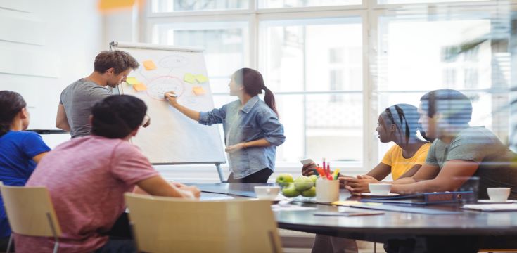 business-executives-discussing-with-their-colleagues-whiteboa-scaled