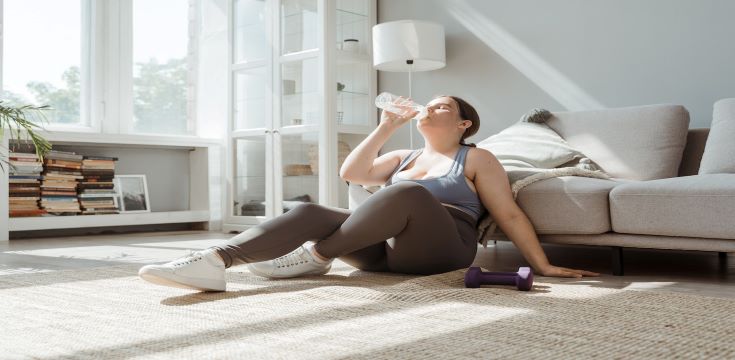 A Woman Sitting on the Floor Drinking Water