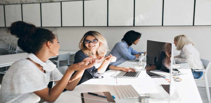 woman-gray-t-shirt-explains-something-blonde-female-friend-indoor-portrait-international-students-with-laptops-preparing-test-together