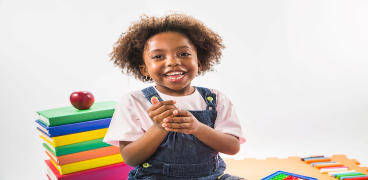 kid-sitting-with-books-smiling-studio