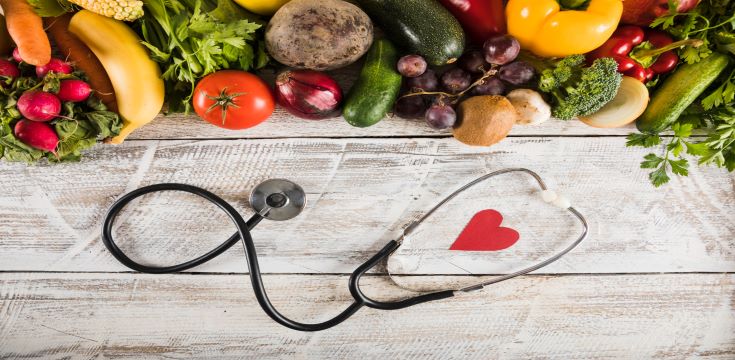 elevated-view-stethoscope-with-heart-shape-near-fresh-vegetables-wooden-desk