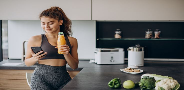 sporty-woman-kitchen-using-mobile-phone