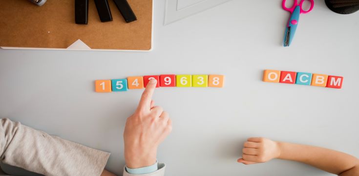 top-view-tutor-teaching-child-desk-about-numbers-letters