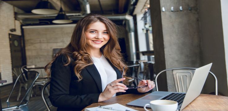 widely-smiling-businesswoman-working-laptop-sitting-cafe