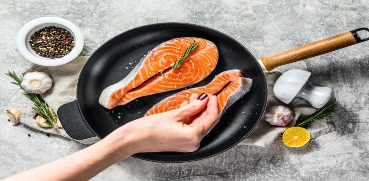 chef-salts-raw-salmon-steak-in-a-frying-pan
