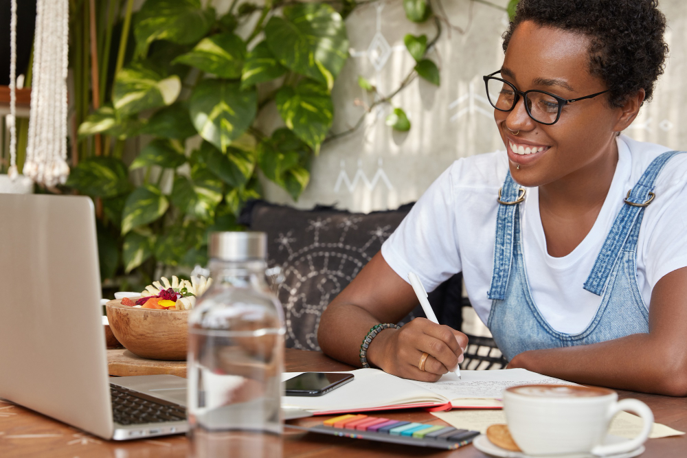 glad-dark-skinned-woman-watches-webinar-online-focused-into-laptop-computer
