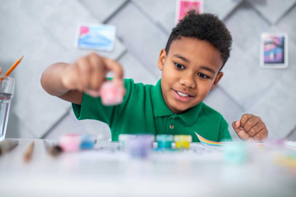 boy-sitting-table-looking-paints-with-enthusiasm