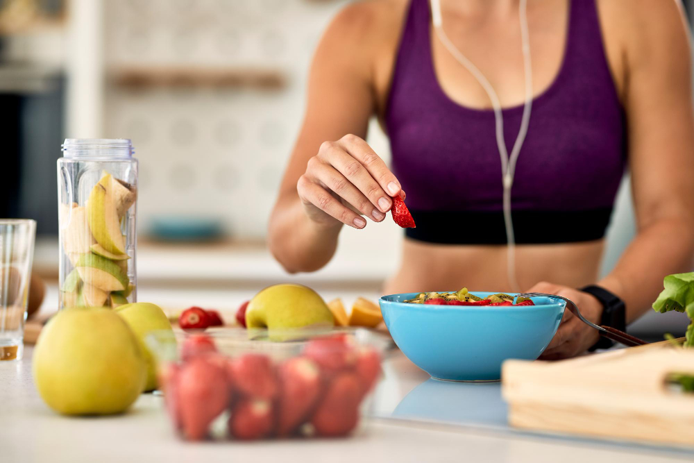 closeup-athletic-woman-adding-strawberries-while-making-fruit-salad-kitchen