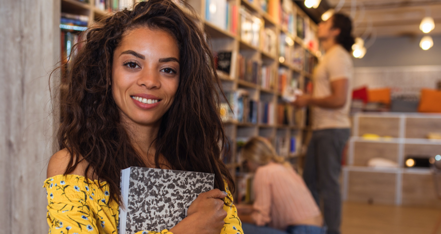 Portrait of young female student standing at library.